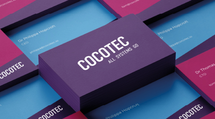 Stack of business cards with bold text. The top card is purple with white text: "COCOTEC ALL SYSTEMS GO." Surrounding cards are blue and pink with text: "Dr Philippa Hopcroft CEO" and "Dr Thomas CTO," along with "tom@cocotec.io" and "philippa@cocotec.io.