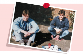 Two people squatting outdoors on pavement. They are wearing casual clothes, and there are cups and a teapot on the ground in front of them. A red pushpin is at the top of the photo. No visible text.